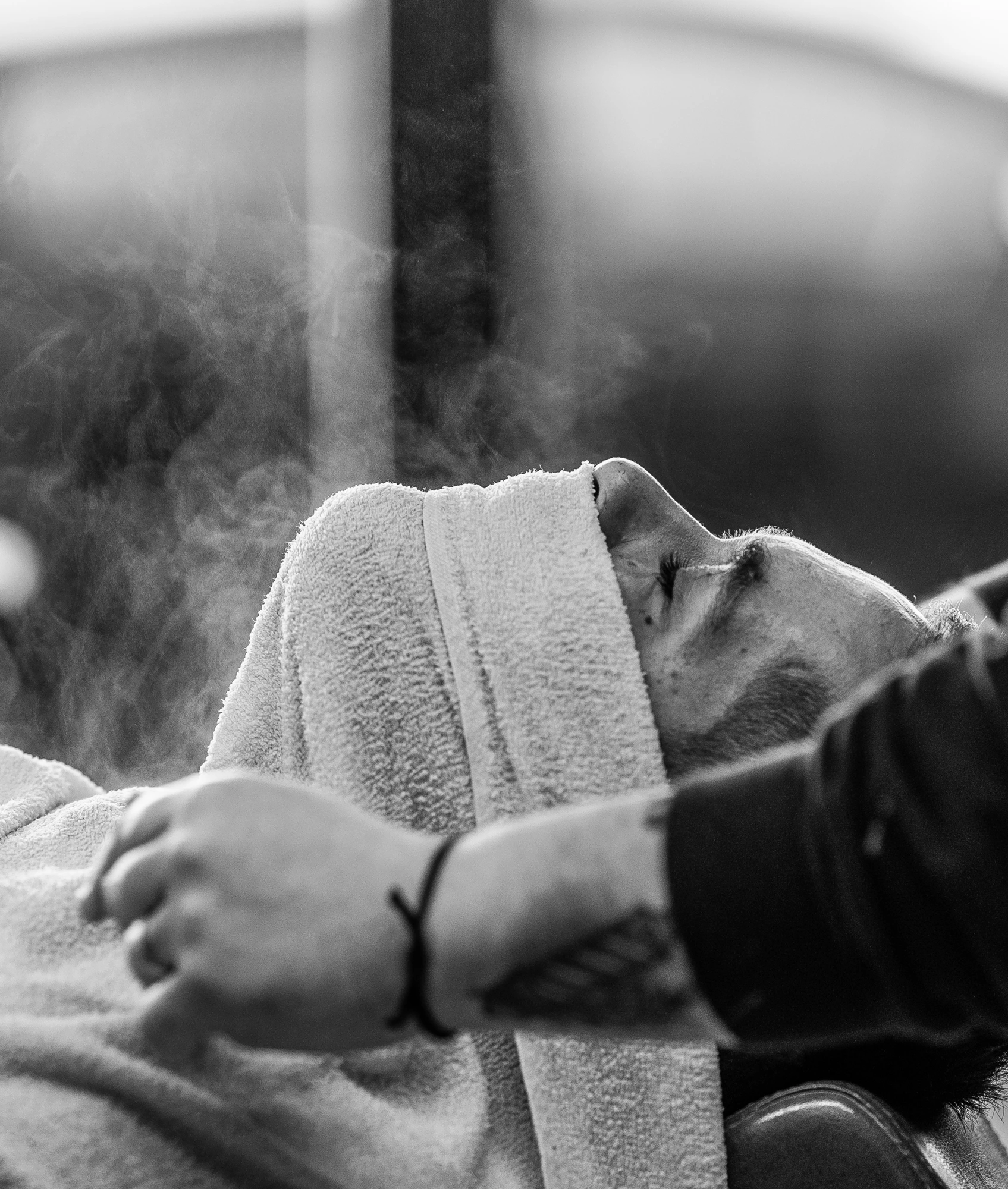 Relaxed face under a hot towel with steam