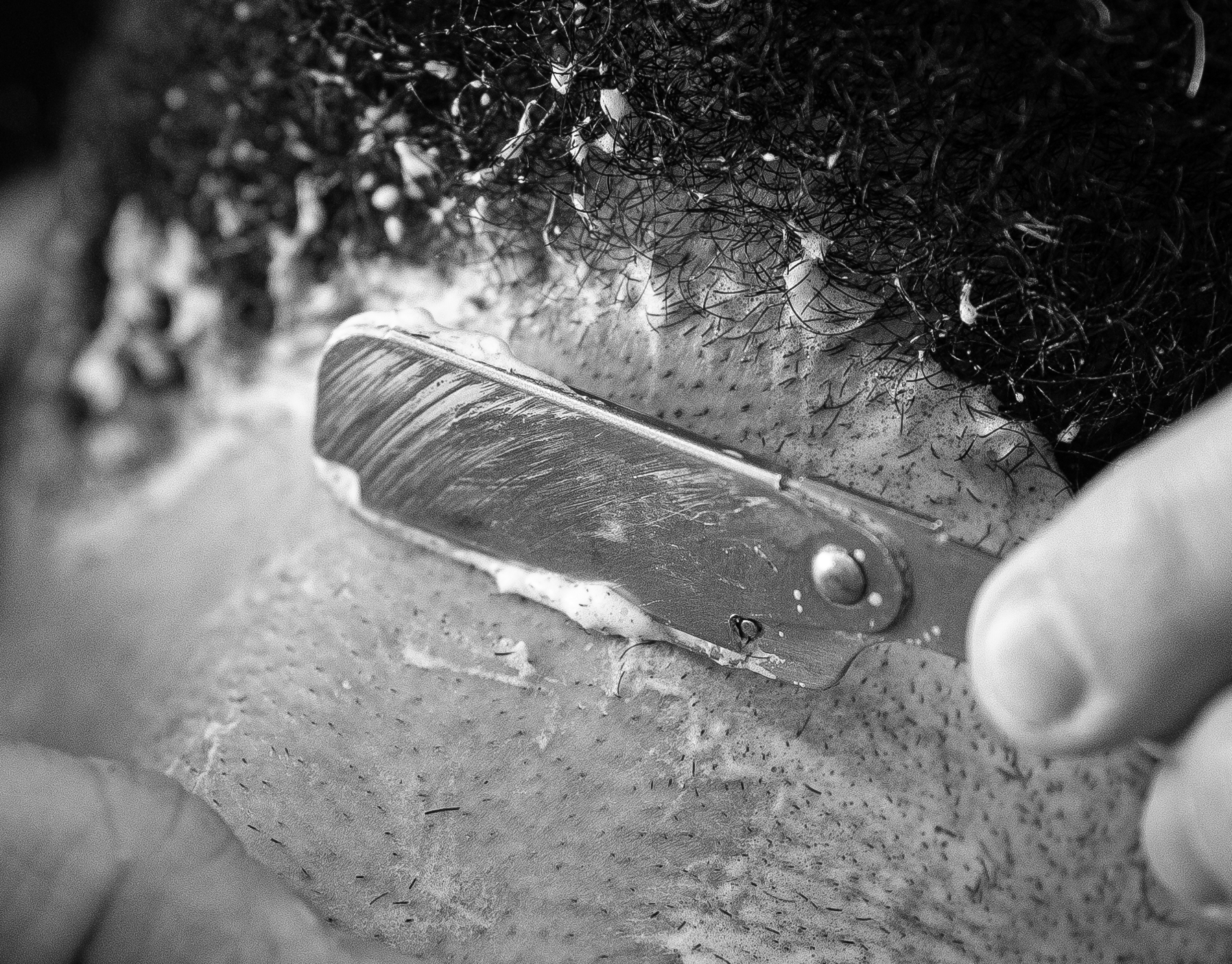 Macro of razor with soap and curly hair