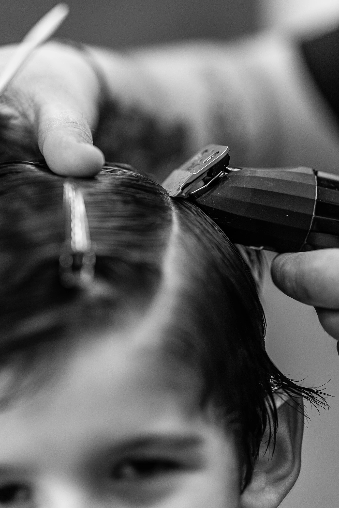 Electric hair clipper trimming temple, face blurred