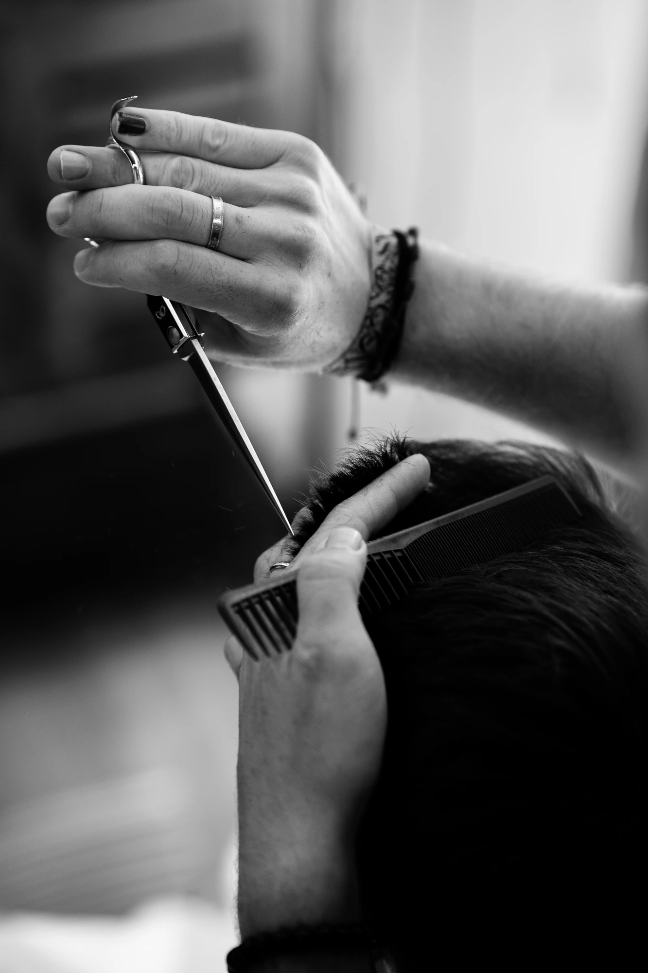 Scissors suspended above the comb, hand with rings