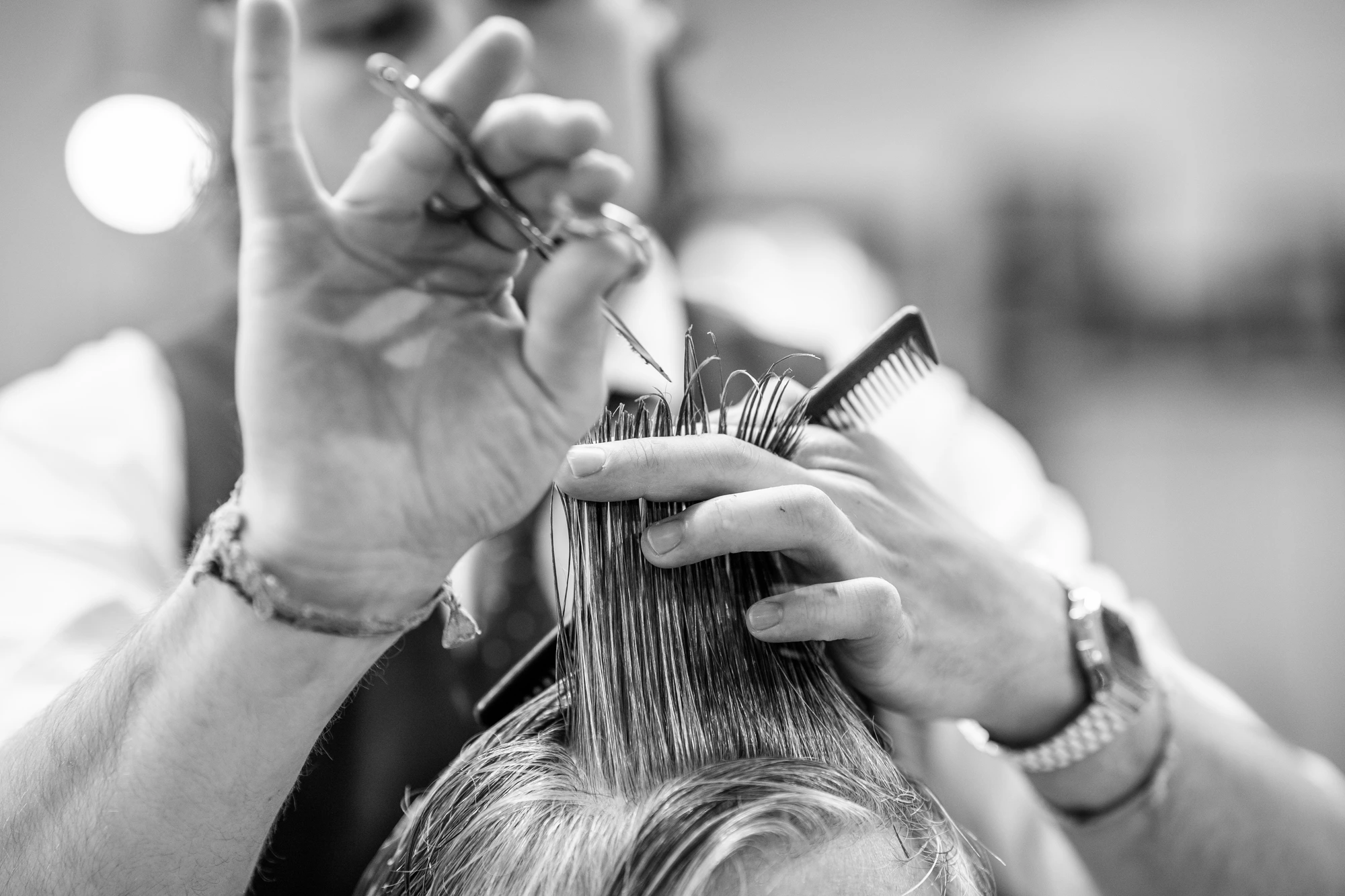 Scissors suspended in the air, lock of wet hair between fingers