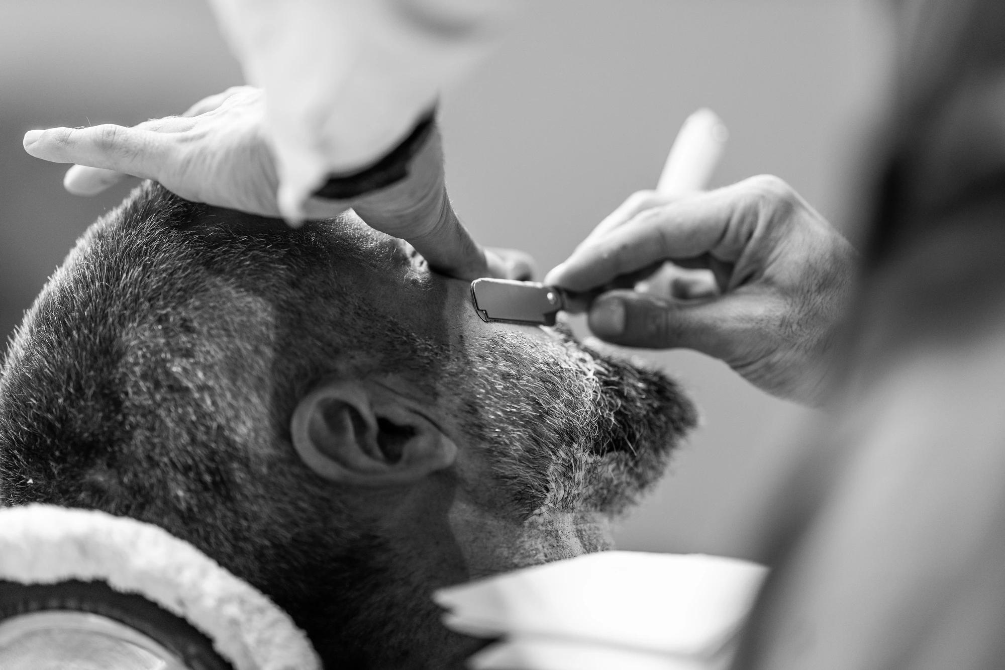 Shaving a thick grey beard with a straight razor, client facing backwards